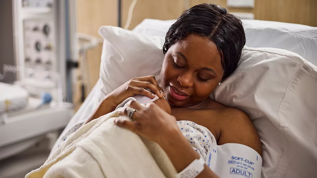 Image of a mother holding an infant in a hospital bed.