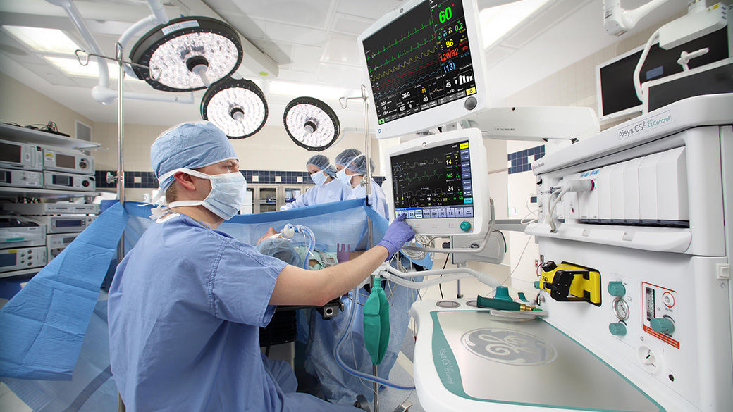 Surgeon in an operating room looking up at a dual patient monitors