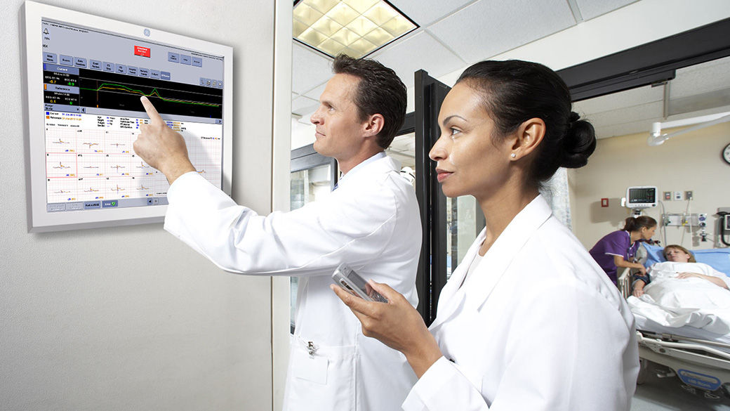 Clinicians reviewing patient vitals.