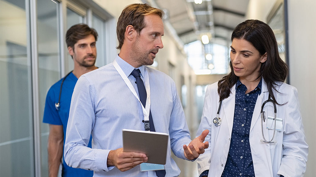 Three clinicians talking in a hallway, looking at a notebook