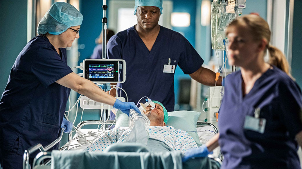 Clinicians moving an intubated patient.