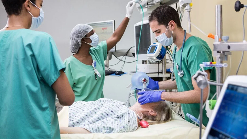 Three clinicians working on a patient in an operating room.