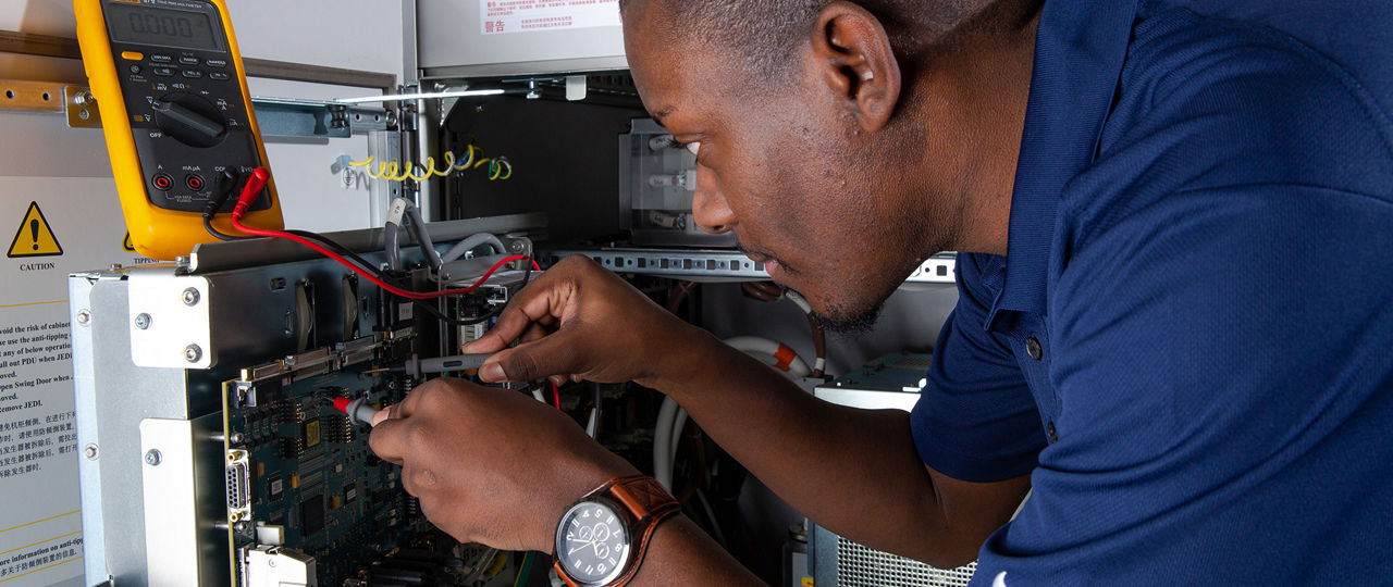 African American technician working on cords on the back of a device