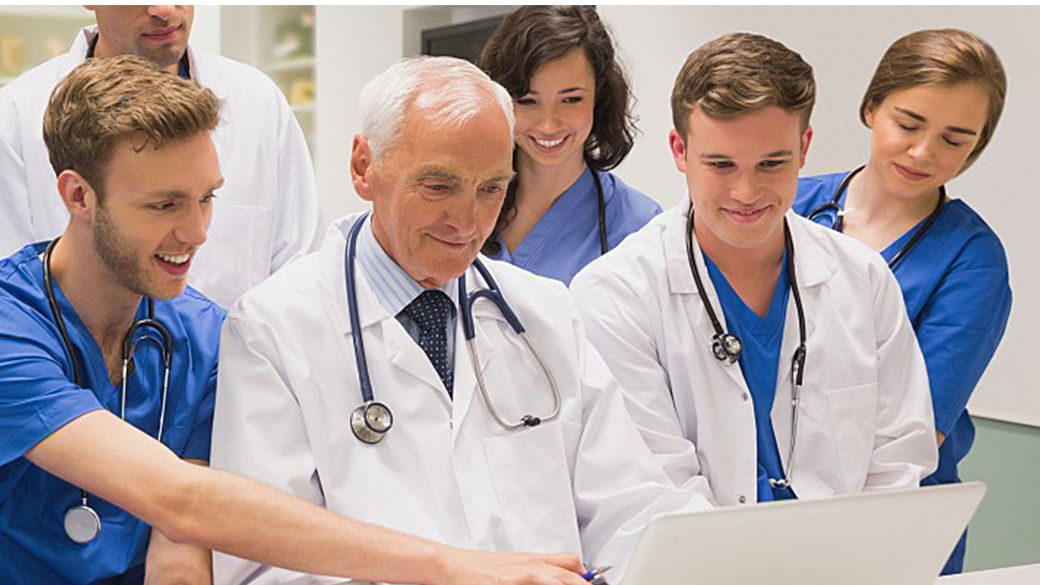 Clinicians working at one laptop.