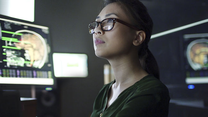 female asian radiologist reviews clinical images in dark