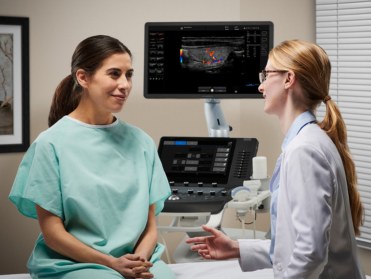 doctor talking to patient about images on versana ultrasound system