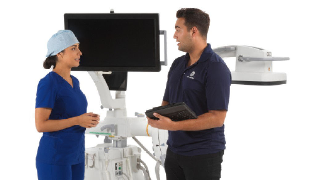 Clinician with an imaging repair technician in front of system