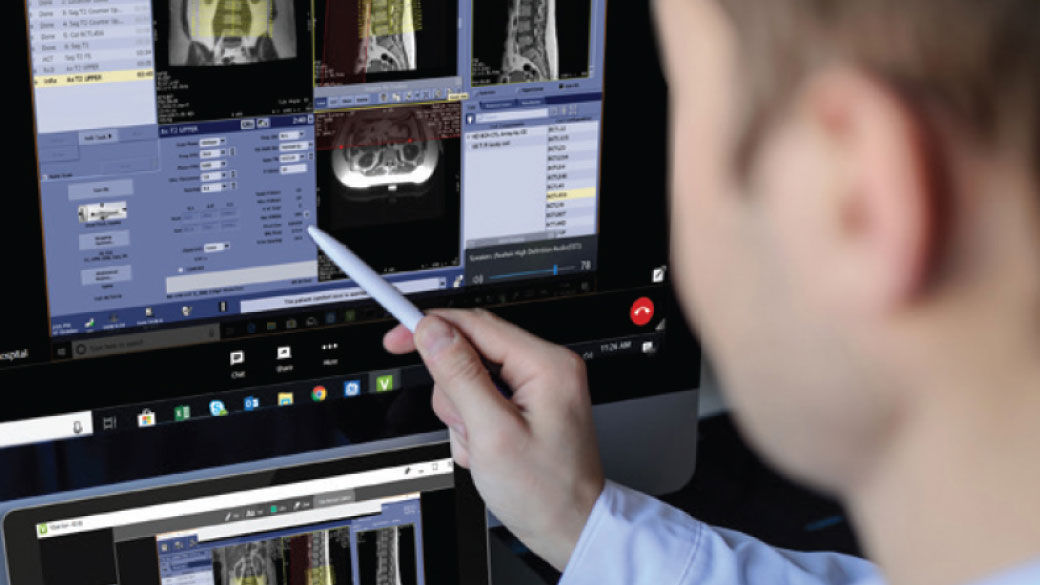 Radiologist holds a tablet while using Digital Expert Access. They can be seen collaborating with a colleague and reviewing a patient radiograph.