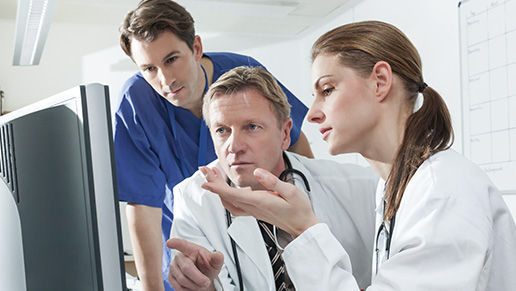 Three physicians looking at a computer monitor