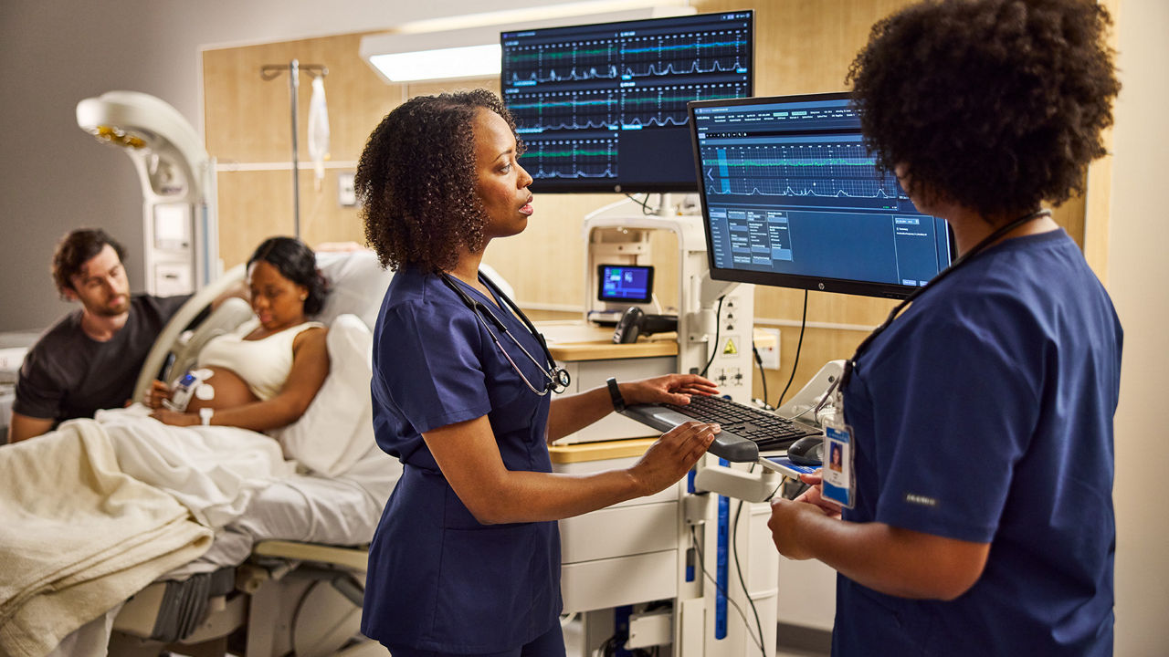 Clinicians monitoring a pregnant patient bedside.