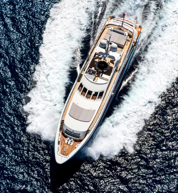 An overhead aerial view of a large yacht cruising at high speed on the open ocean