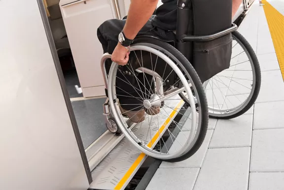Person in wheelchair rolling onto train from station platform.