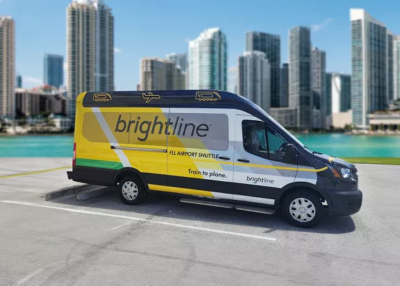 A Brightline shuttle with the Miami skyline in the background.