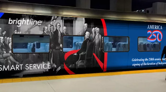 A woman walking past the Brightline America250 "Freedom Express" train.
