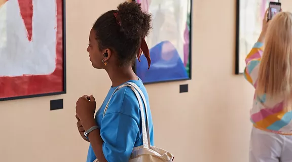 Diverse group of teenagers looking at abstract art in art gallery or museum standing in row with African American girl in foreground