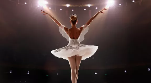 A girl dressed in white performing in front of a big crowd