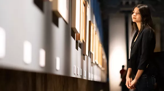 A woman standing in a museum, admiring framed art on the walls