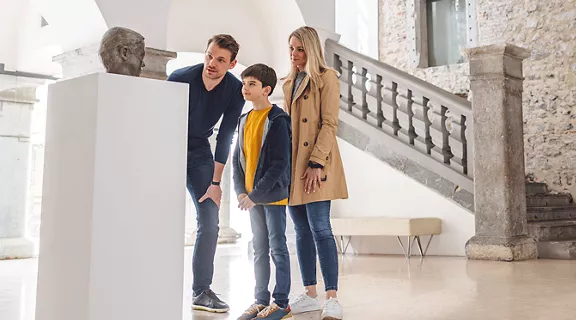 A father, mother, and son viewing a sculpture at an art museum