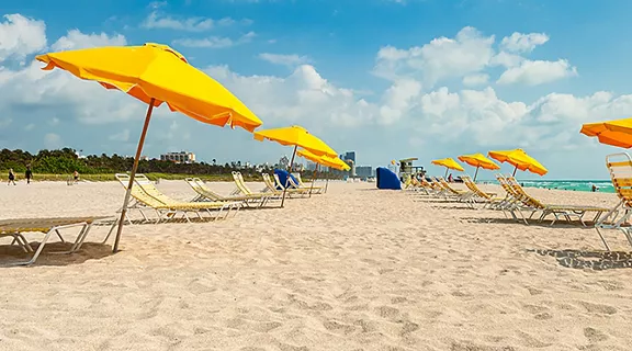 Colorful umbrellas and lounge chairs along the the shoreline in popular Miami Beach.