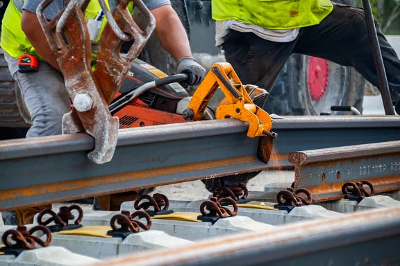 Construction workers trimming rail systems for the Brightline West project.