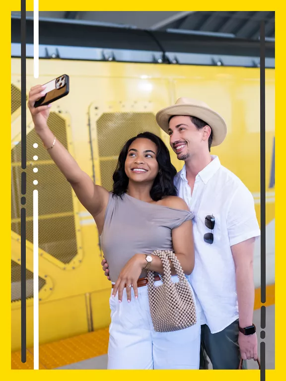 A young couple poses together while taking a selfie with a smartphone. 