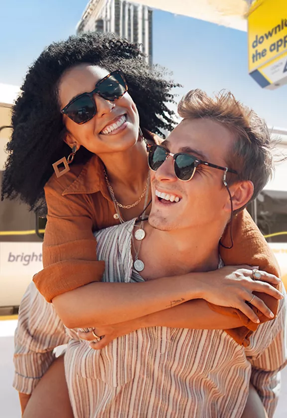 A man and woman hugging and smiling on the Brightline train platform.