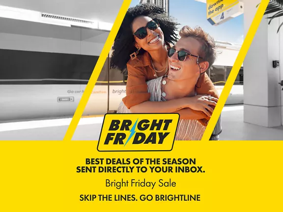 A couple hugging and smiling while standing on a Brightline train platform.
