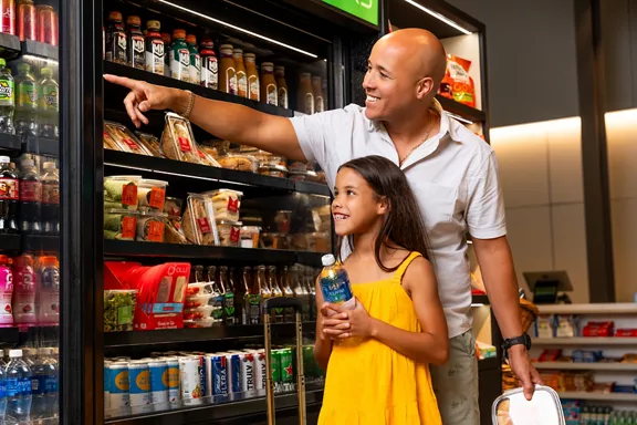 A man pointing out an item to his young daughter as they browse the Brightline MRKT store.