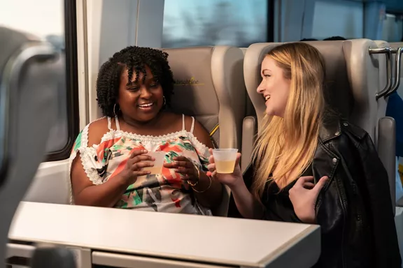 Two women enjoying drinks during their Brightline train ride.