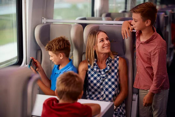 A family talking and playing games while taking a ride on a Brightline train.