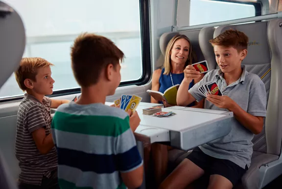 A family playing cards while taking a ride on a Brightline train.