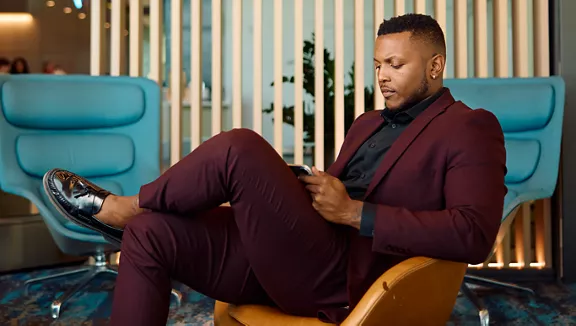A man watching a video on his phone in the Premium Lounge of a Brightline train station.