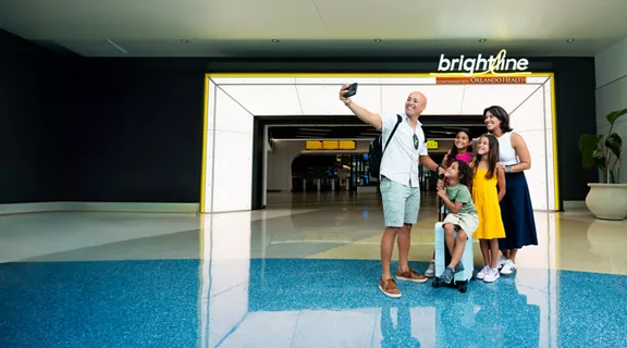 A family posing for a selfie in the lobby of the Brightline Orlando station.