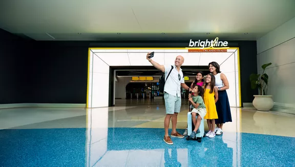 A family posing for a selfie in the lobby of the Brightline Orlando station.