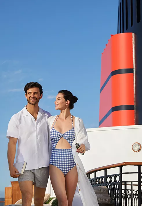 Two guests walking in bathing suites atop a cruise ship deck
