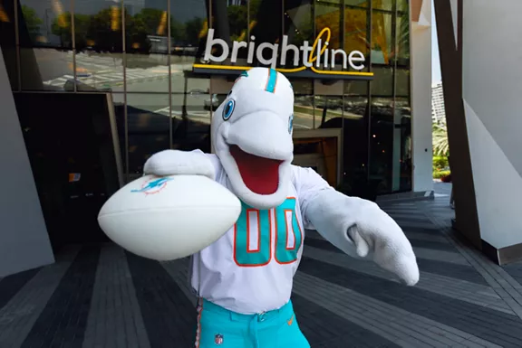 Miami Dolphins mascot T.D. posing with a white Miami Dolphins football outside of Brightline MiamiCentral station