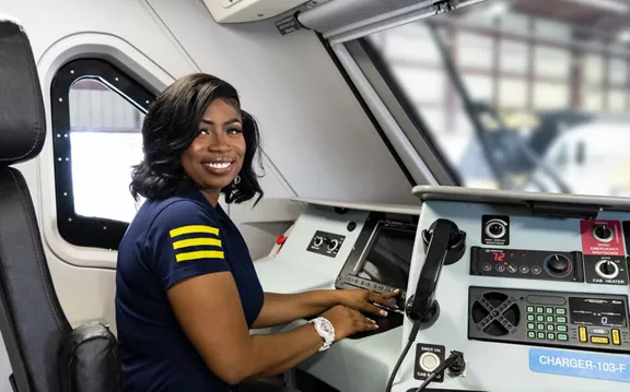 A smiling Brightline employee sitting in the train locomotive