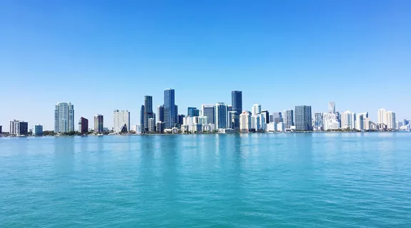 A water-level view of the downtown Miami skyline in the distance on a bright sunny day.