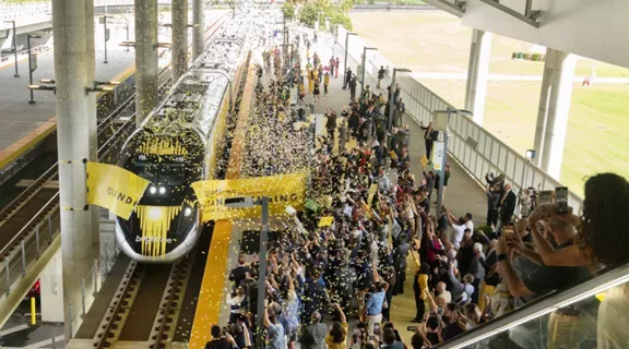 Brightline Orlando Grand Opening fir st train arriving in station and breaking ribbon with crowds on platform.
