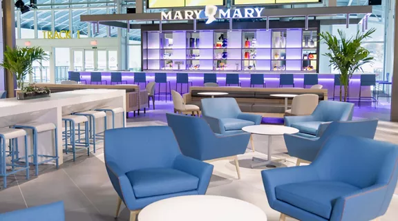 Blue chairs and tables placed outside of Mary Mary bar with Mary Mary neon sign displaying