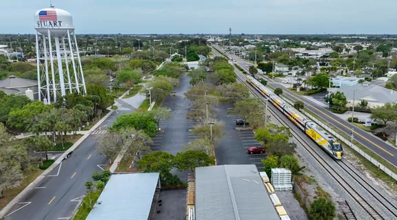 Aerial view of a Brightline train passing near a water tank in the city of Stuart, Florida