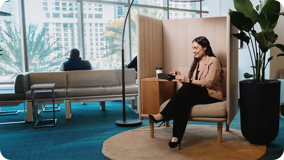 A woman sitting on a high back chair at the Brightline waiting area.
