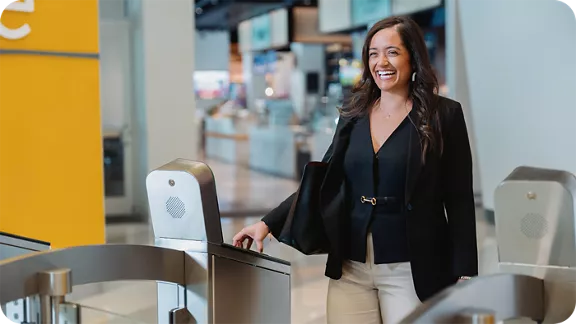 A woman smiling while swiping her phone on the turnstile lane at the Brightline train station