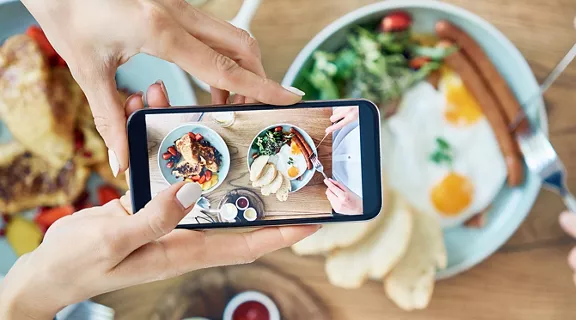 Woman taking photo of breakfast served in cafe. Couple having meal together