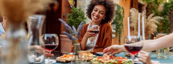 A lady smiling and drinking her wine with her friends