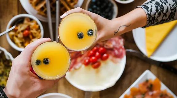 A young couple toasting mimosas over the table at brunch