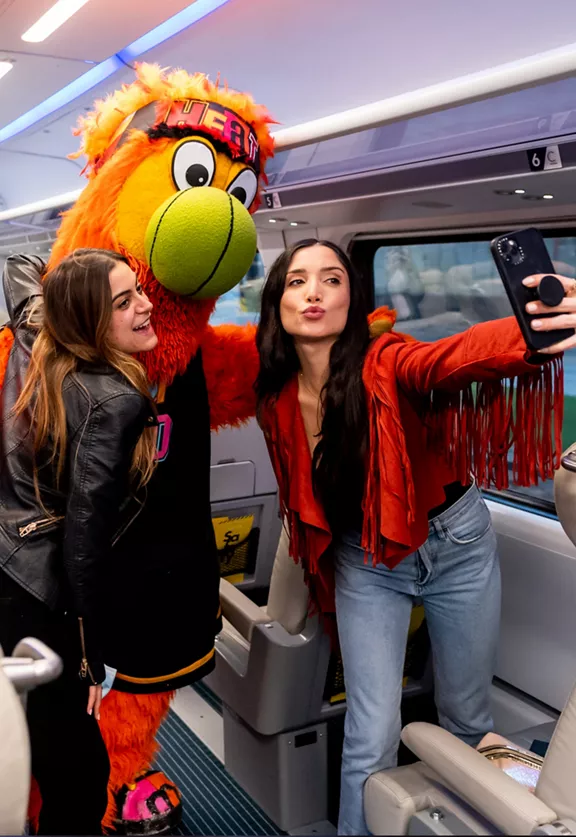Two women pose for a selfie with Miami Heat's mascot, Bernie.