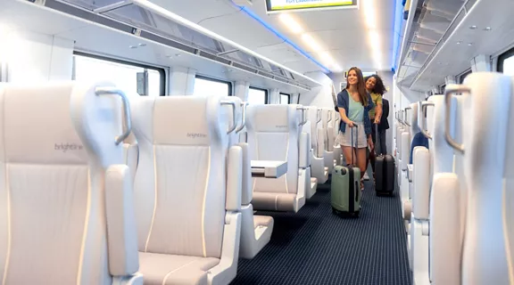 Guests rolling their carry-on baggage onto a Brightline train