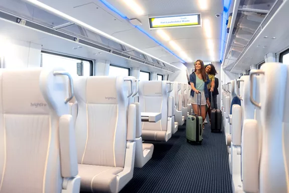 Guests rolling their carry-on baggage onto a Brightline train