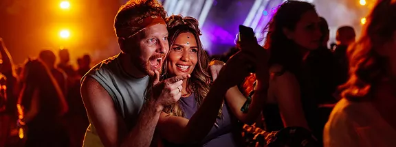 Two friends taking a selfie on a smartphone at a concert